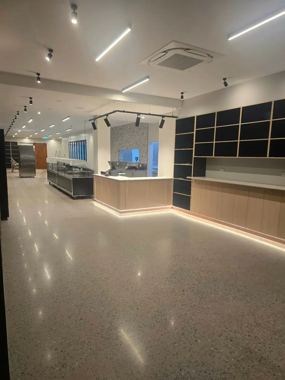 Finished retail interior with polished concrete floor, service counter and shelving