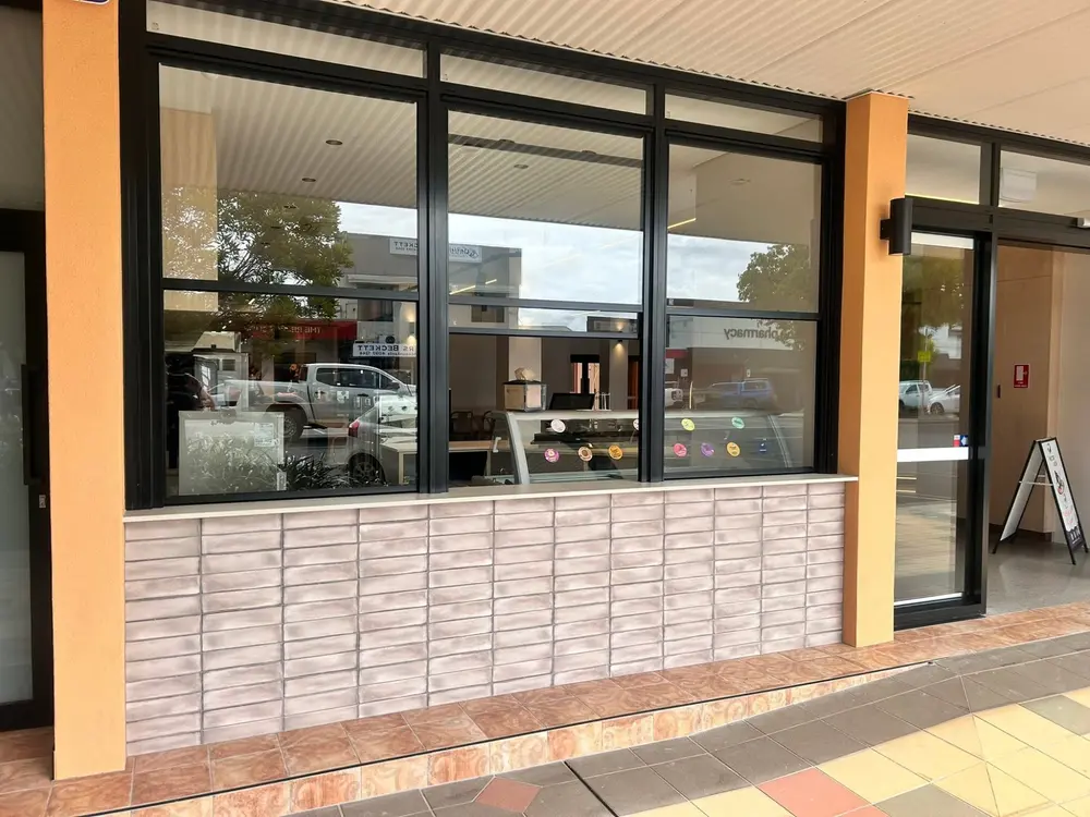 Completed commercial shopfront with black-framed windows and stone-look facade