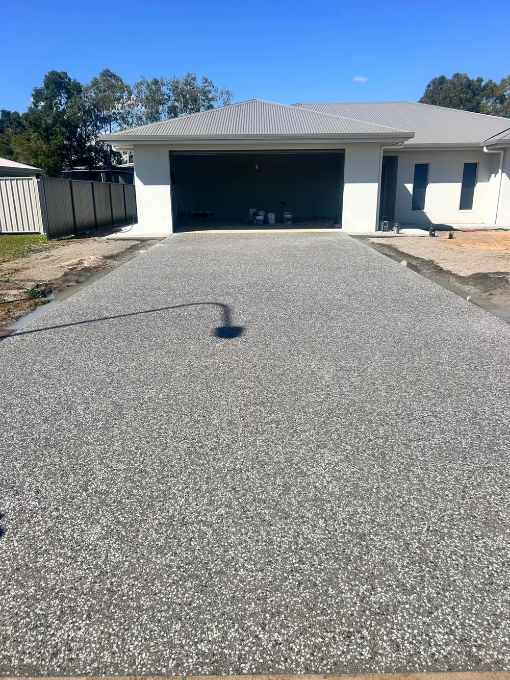 Finished exposed aggregate concrete driveway leading to a completed home