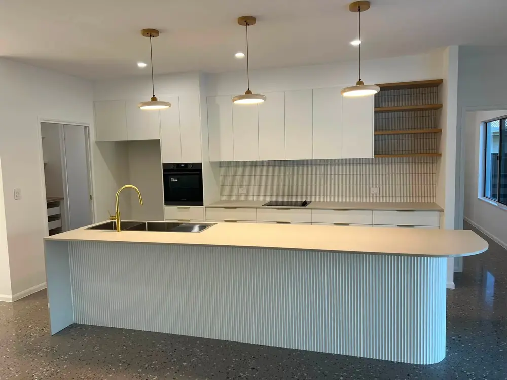 Finished kitchen with timber cabinetry, white island and pendant lights