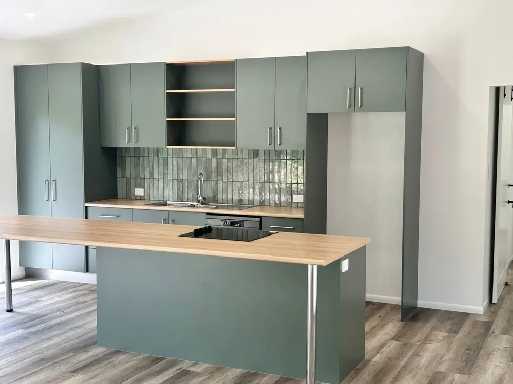 Finished kitchen with green cabinetry, timber island and large windows