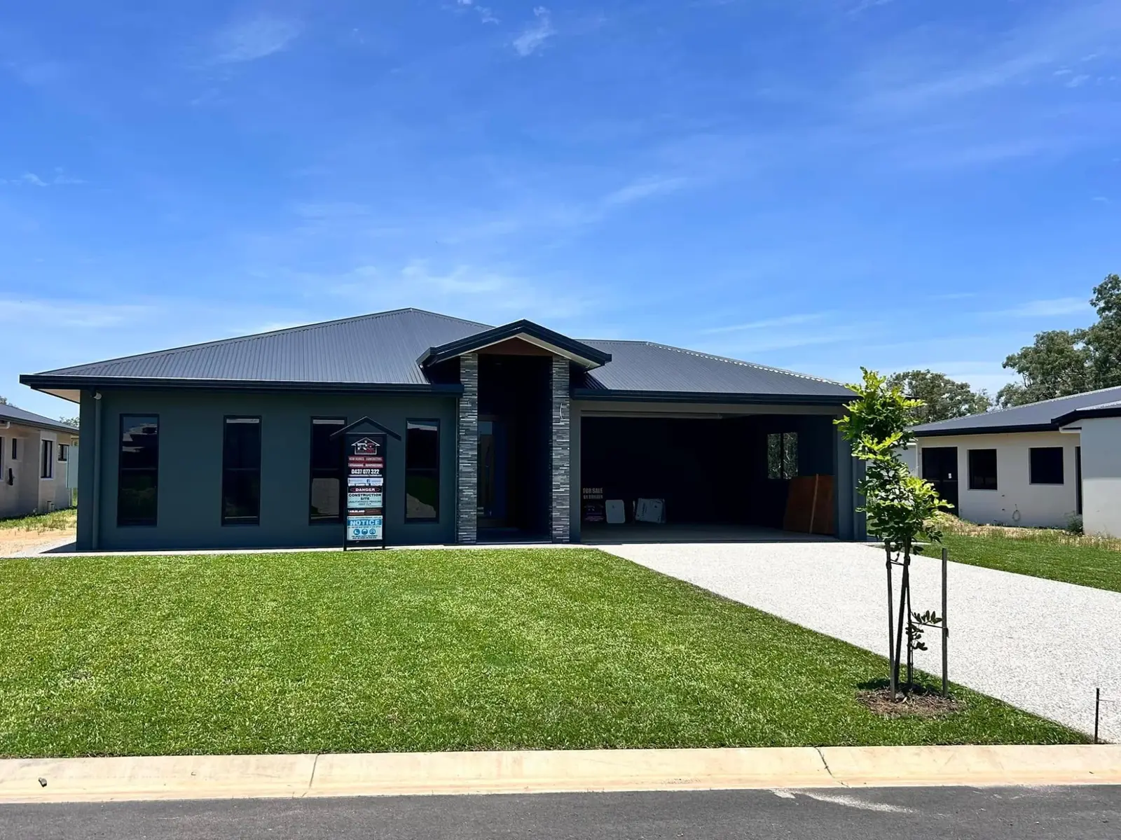 Finished contemporary home with dark facade, front lawn and concrete driveway